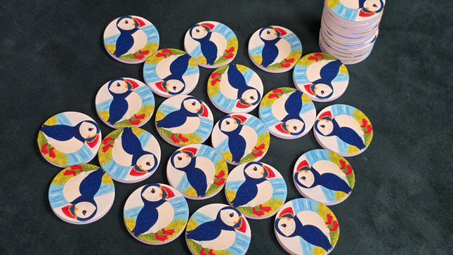 Colorful IsTap puffin magnets spread on a dark surface